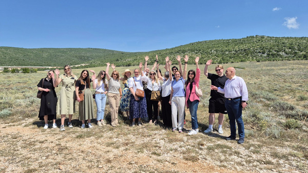 Group of people standing in a field waving.