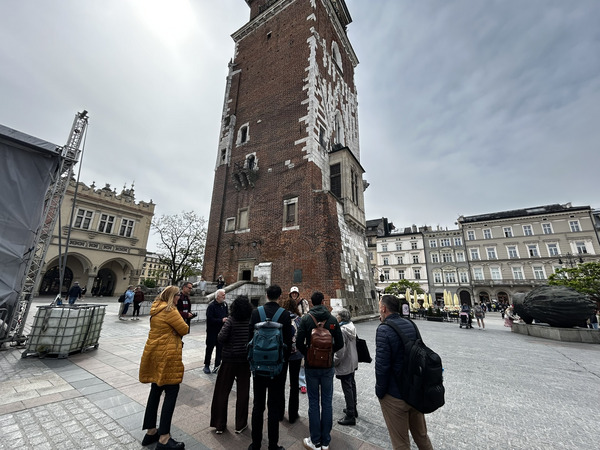 A group of people standing in front of an ancient tower.