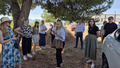 Group of people standing outdoors under some trees.